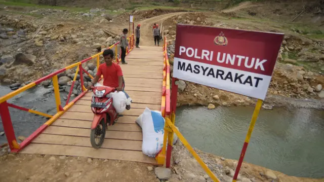 Warga melintasi jembatan darurat bantuan Polri di Palembayan, Agam, Sumatera Barat, Jumat (23/1/2026).