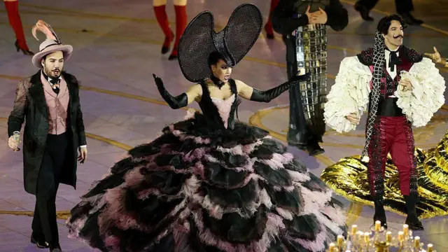 足もとで大きく広がっているドレスを着た人や、羽根の付いた帽子をかぶって黒っぽい衣装でめかした人などがパフォーマンス披露している