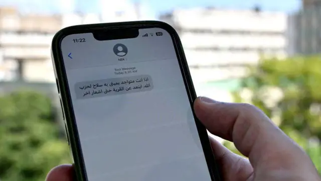 A hand holds a mobile phone with a message written in Arabic on it. අරාබි භාෂාවෙන් ලියා ඇති පණිවිඩයක් සහිත ජංගම දුරකථනයක් අල්ලාගෙන සිටින අතක්