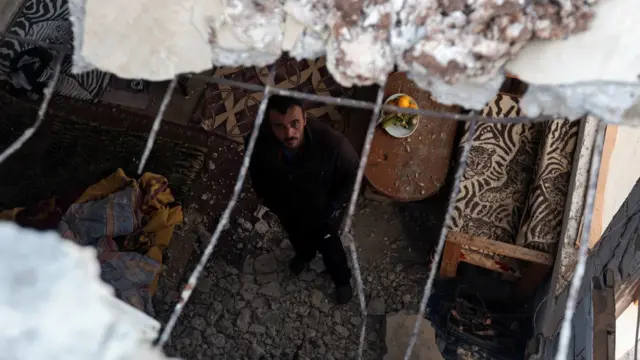 رجل يعاين آثار القصف في منزل