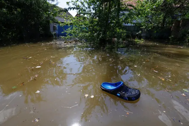 A slipper is seen adrift in a flooded residential area of Nova Kakhovka