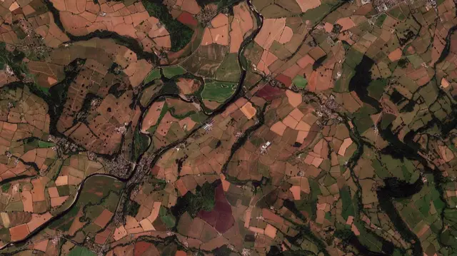 イングランドとウェールズの平地の空撮写真。広範囲が茶や赤になり、ところどころに緑の草地が見える