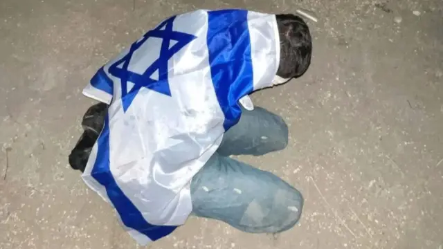 A Palestinian detainee pictured with an Israeli flag draped over their back