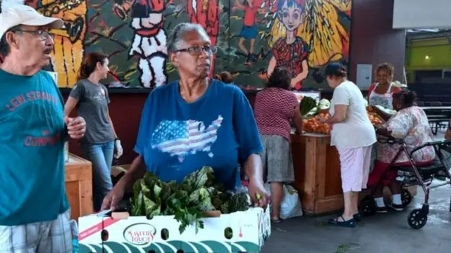 Mulher carrega caixa com verduras