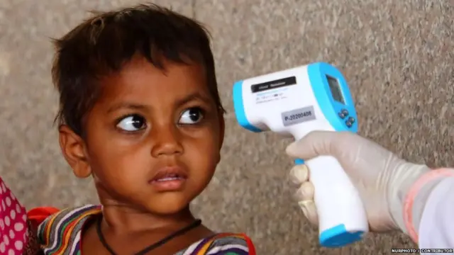 बच्चे के शरीर का तापमान लेता हुआ स्वास्थ्य कर्मी