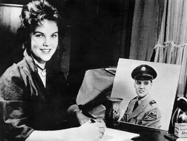 Priscilla frente a una foto de Elvis Presley uniformado