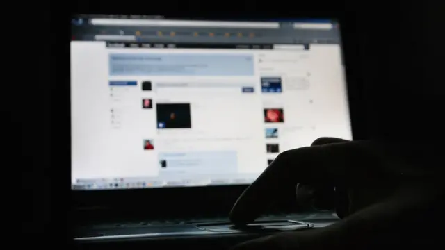 Alguien mirando una página de Facebook en la oscuridad