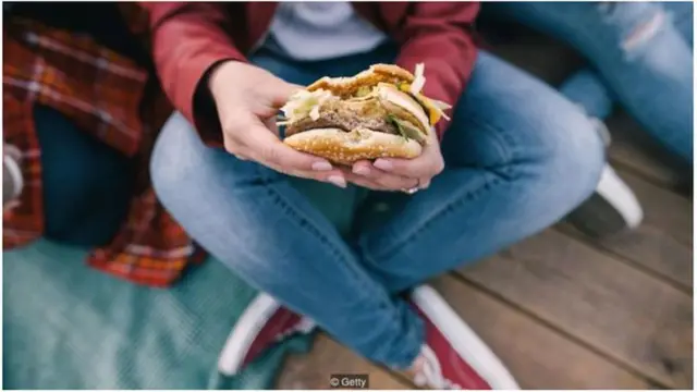 pessoa comendo hamburguer