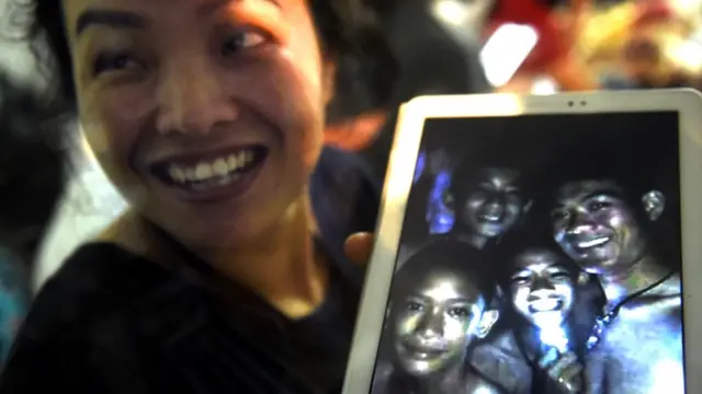 Член семьи одного из подростков показывает сделанную в прошлом году фотографию, на которой - четверо из 12 подростков