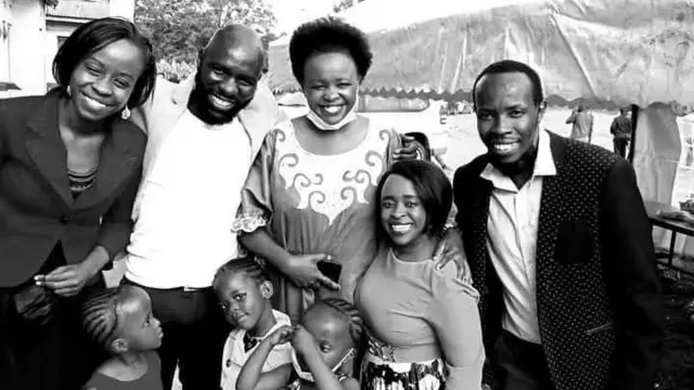 Charity, her brother Tom (for black jacket), and oda siblings and their children smile as they pose for a picture.