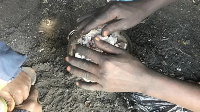 Pesin dey warm hand over di fire