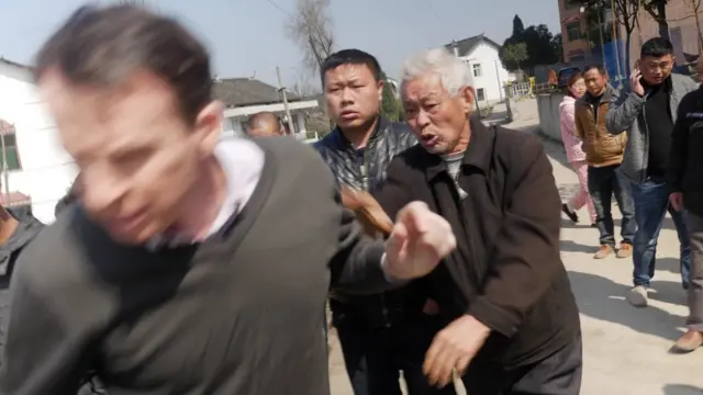 Picture of BBC journalist John Sudworth being forced away from a Chinese village