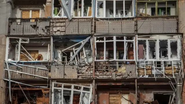 Un edificio de apartamentos gravemente dañado con ventanas rotas.