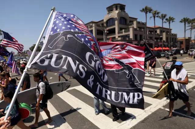 Um apoiador pró-Trump agita uma bandeira com os dizeres "Deus, Armas e Trump"