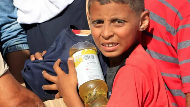 طفل في غزة يحمل مساعدات غذائية