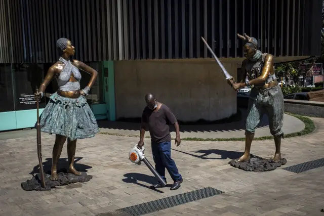 A caretaker uses a leaf blower between two new bronze sculptures by South African artist Nandipha Mntambo at the Circa Gallery as part of the Keyes Art Mile in Johannesburg, South Africa, 18 November 2021.