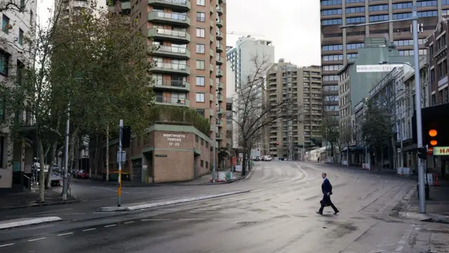 Um homem atravessa uma rua deserta no centrobetano raspadinhaSydney durante lockdown