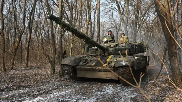 যুদ্ধের ময়দানে একটি ট্যাঙ্ক নিয়ে যোদ্ধাদের দেখা যাচ্ছে।