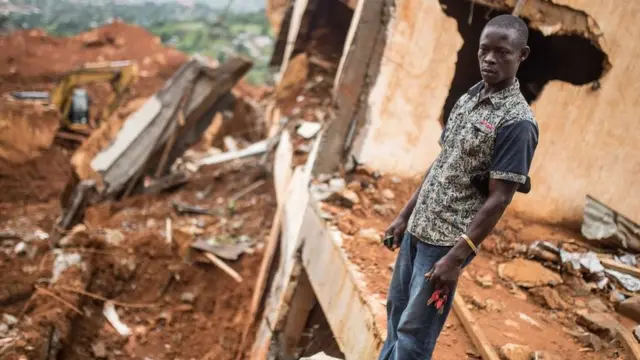 ألفريد جوني يقف أمام حطام منزل شقيقه