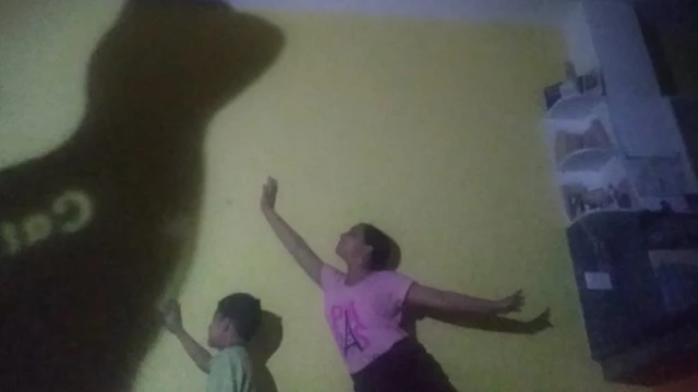 Valeria com o seu irmão brincam com a sombra da gata da família