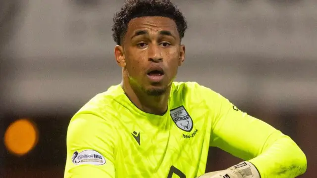 A goalkeeper wearing a bright yellow jersey during a match.