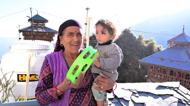 कन्दाड़ गाँव की अनारी देवी अपी गोद में लिए बच्चे को एक खिलौने से बहलाती हुईं.