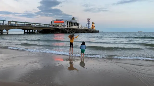 Dos chicas en primer plano, chapoteando en el mar junto al muelle de Bournemouth