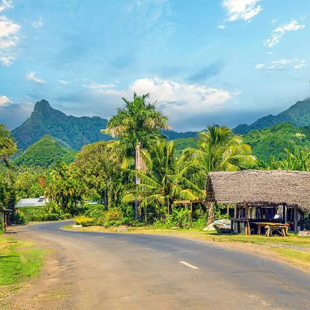 Vista de estrada em meio à natureza, com montanhas ao fundo
