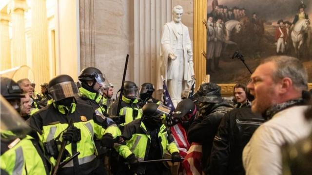 暴力事件是在美國歷史人物和場景的超現實背景下發生（圖為警察在國會大廈內的亞伯拉罕·林肯雕像旁邊與支持特朗普的暴徒對峙）。