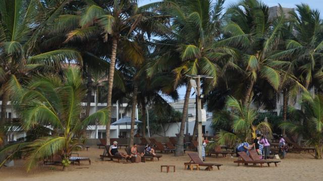 Turistas sentados em praia do Sri Lanka