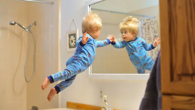 Wil volando en sus piyamas mirando su imagen en el espejo del baño