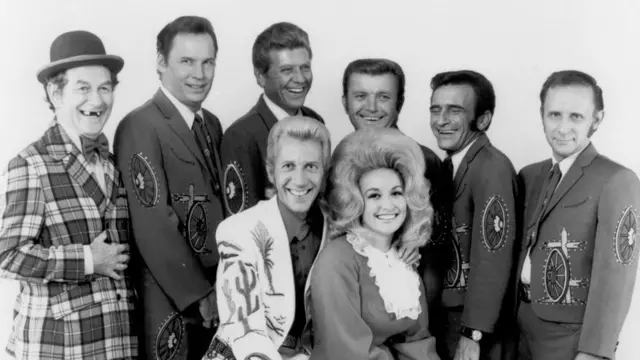 Los cantantes de música country y colaboradores Porter Wagoner y Dolly Parton posan para un retrato junto a su banda de acompañamiento, The Wagonmasters, hacia 1968.