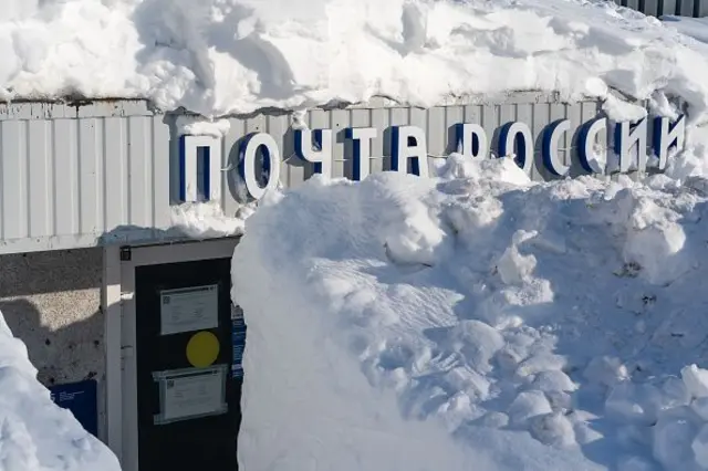 Kar üzerinde Rusça yazılar olan binanın girişini tamamen kapatmış, binanın kapısı karların arkasından kısmen görülüyor.