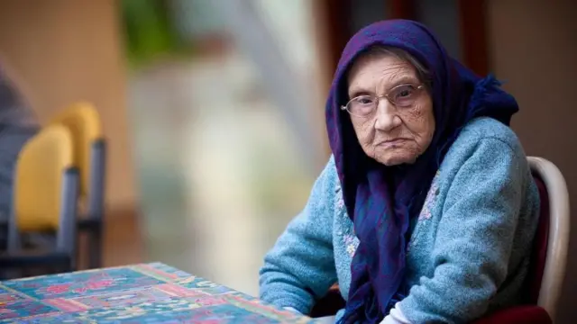 Una señora mayor sentada a una mesa