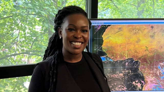 Sarah Kimani, du département météorologique kenyan, devant une carte météorologique.