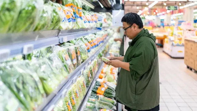 Чоловік у супермаркеті біля стелажів із зеленню
