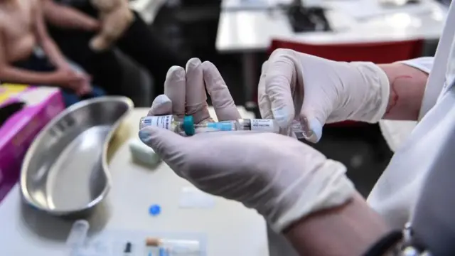 यूरोप के रोमानिया में स्वास्थ्यकर्मी वैक्सीन देते हुए