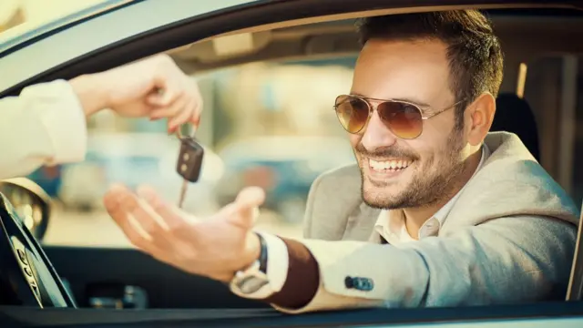 Hombre recibiendo llave de su nuevo carro