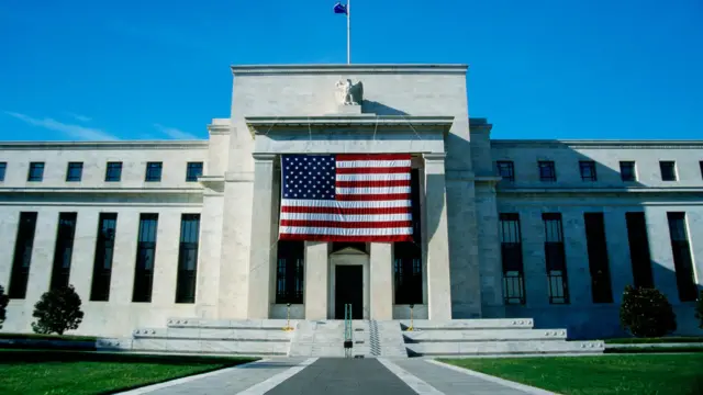 El edificio de la Reserva Federal de Estados Unidos con una bandera del país en frente. 