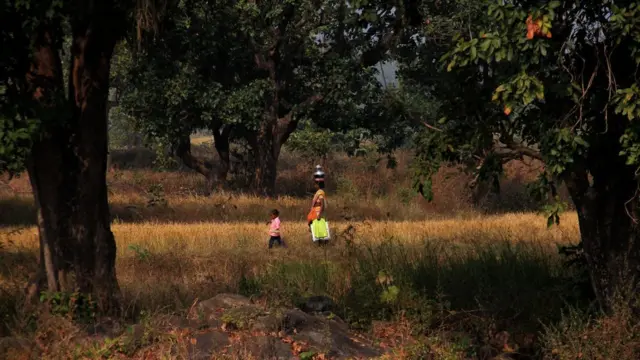 A woman walking to work with her child in Odisha state
