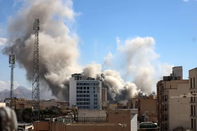 কয়েকটি ভবনের পেছন থেকে বিস্ফোরণের কালো ও ধূসর ধোঁয়া বের হচ্ছে