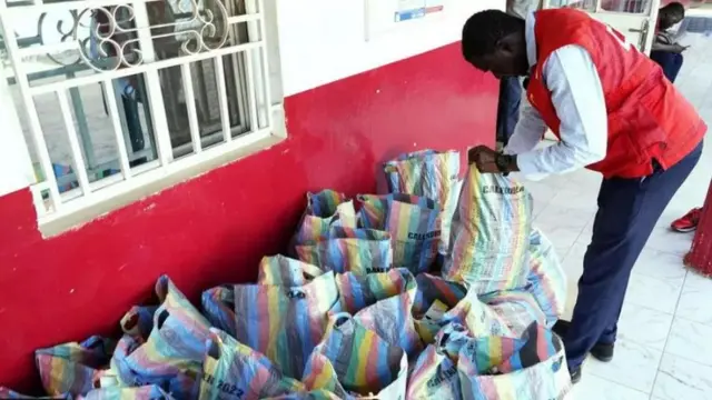 A﻿nggota Palang Merah Gambia memeriksa karung-karung berisi obat batuk yang dikumpulkan.