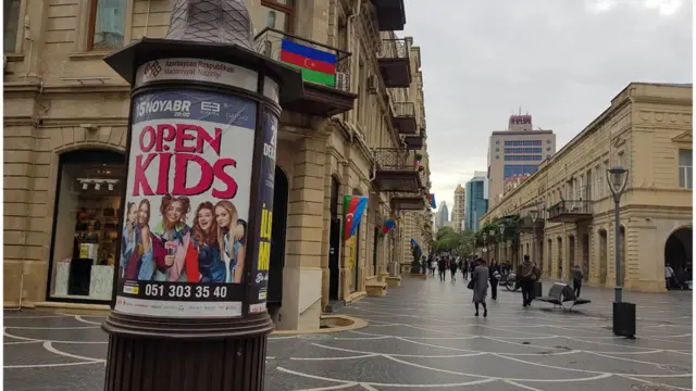 Прошлогодняя афиша на улице Низами, позади здание с флагами