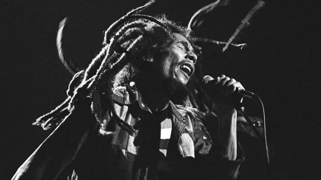 Bob Marley en pleno concierto. Tiene los ojos cerrados y cabellos rastas revueltos.