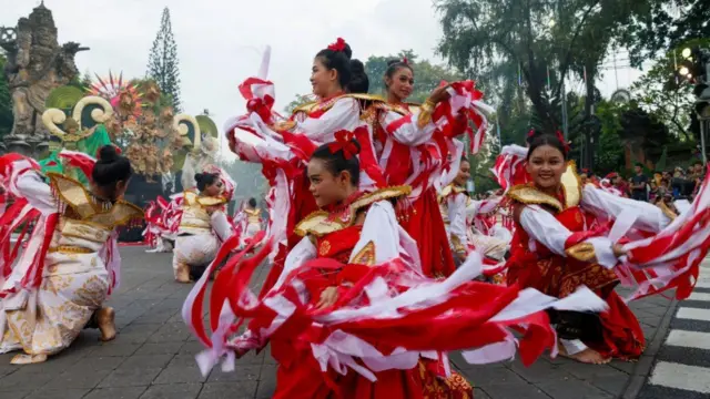 赤と白の衣装や髪飾りを着けた女性ダンサーが躍っている