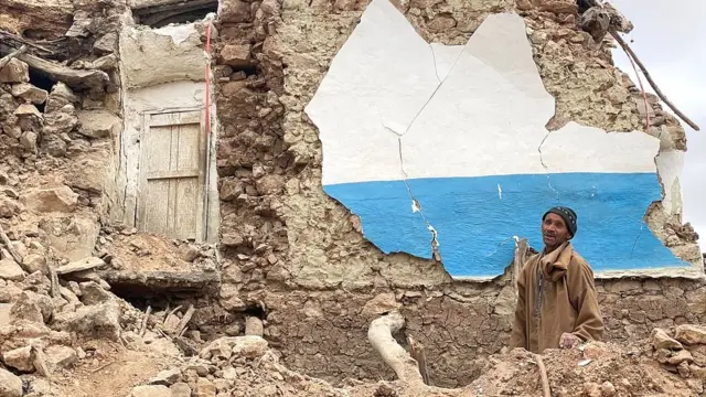 Un homme se tient à côté de ce qui reste d'une maison dans le village montagneux de Douzrou, au Maroc.