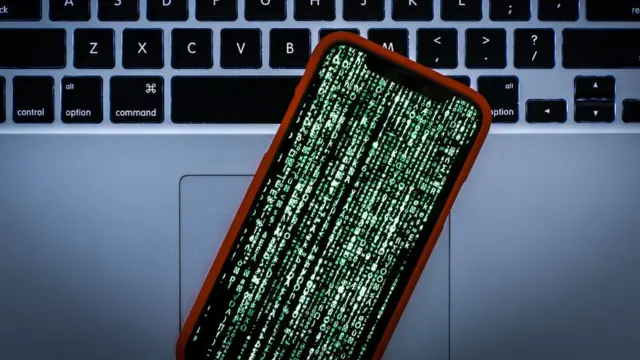 Un teléfono cifrado delante de una computadora.