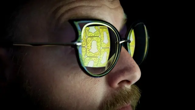 Hombre con bigote y gafas de sol en las que se refleja el logo de Snapchat
