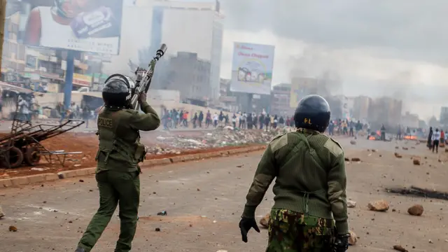 La police anti-émeute kenyane, en uniforme, utilise des gaz lacrymogènes pour disperser les manifestants en colère à Waiyaki Way à Kangemi.