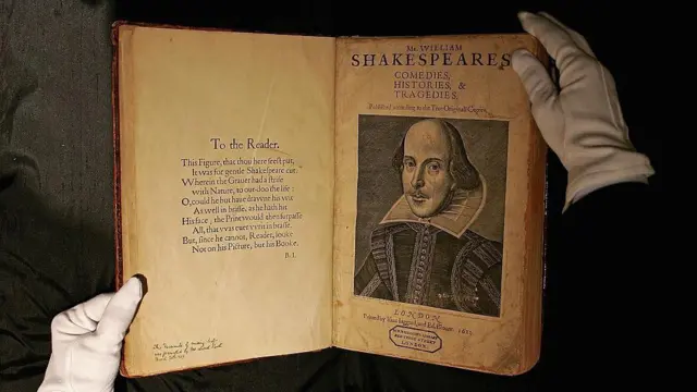 A primeira edição original de uma obra de Shakespeare, aberta entre as mãos cobertas por luvas de um funcionário de uma casa de leilões